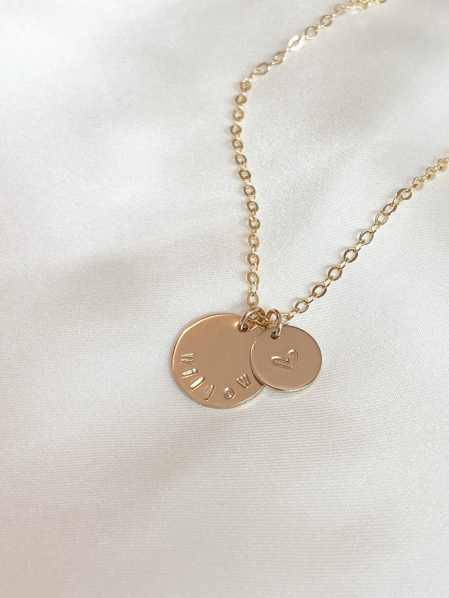 Gold necklace. On large disc it says Willow, small disc has a heart.